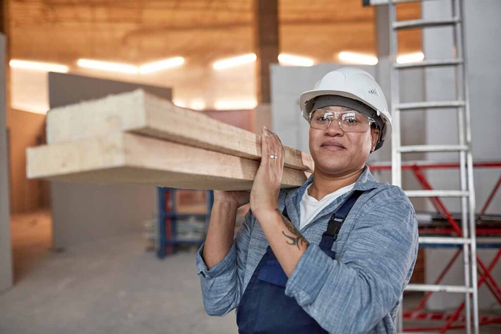 Warehouse worker carrying planks of wood